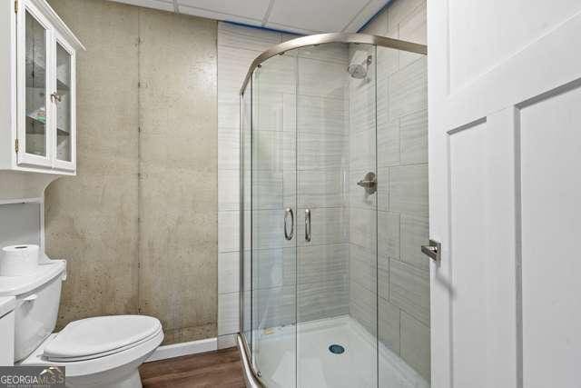 bathroom featuring a drop ceiling, toilet, and walk in shower