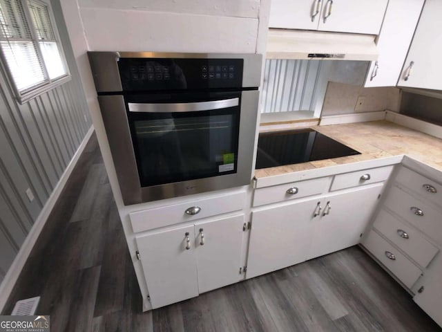 kitchen featuring black electric cooktop, dark hardwood / wood-style flooring, white cabinets, and oven