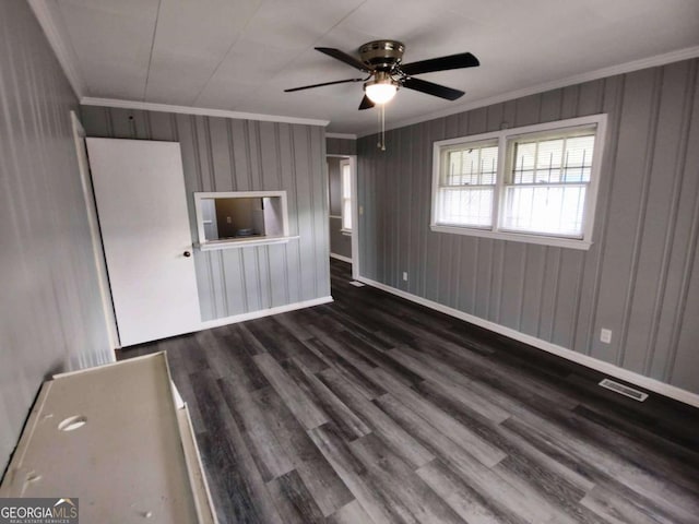 empty room with ceiling fan, dark wood-type flooring, and crown molding