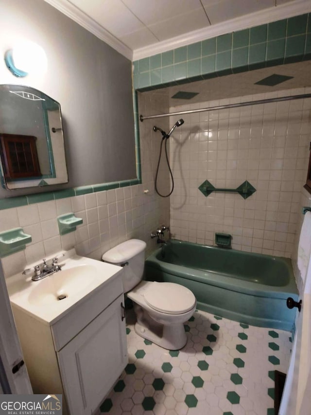 full bathroom with tiled shower / bath combo, vanity, tile walls, toilet, and crown molding