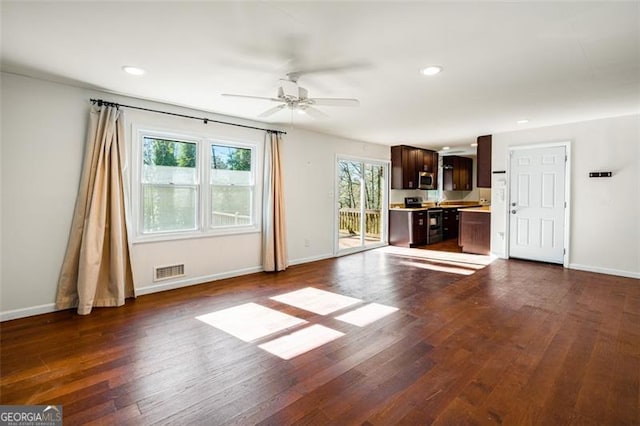 unfurnished living room featuring dark wood-type flooring and ceiling fan