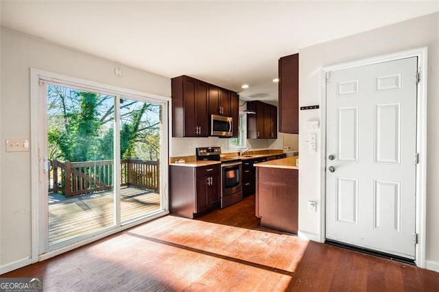 kitchen featuring sink, dark hardwood / wood-style flooring, dark brown cabinetry, and appliances with stainless steel finishes