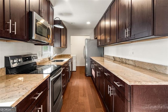 kitchen featuring sink, light stone counters, dark brown cabinets, dark hardwood / wood-style flooring, and appliances with stainless steel finishes