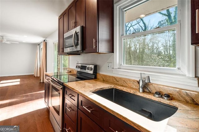 kitchen featuring stainless steel appliances, light stone countertops, ceiling fan, dark hardwood / wood-style floors, and sink