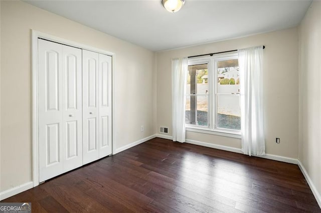 unfurnished bedroom with dark wood-type flooring, a closet, and multiple windows