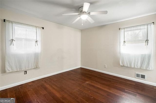 empty room with a wealth of natural light, ceiling fan, and dark hardwood / wood-style flooring