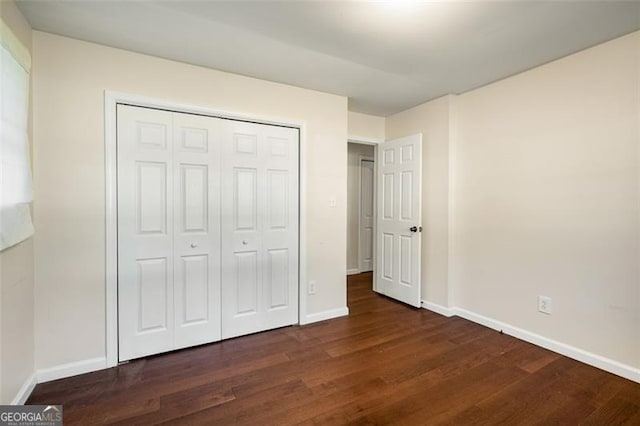 unfurnished bedroom with dark hardwood / wood-style flooring and a closet