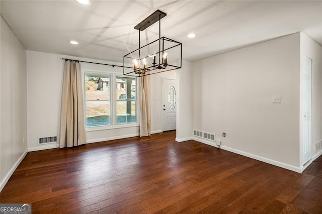 empty room featuring an inviting chandelier and dark hardwood / wood-style floors