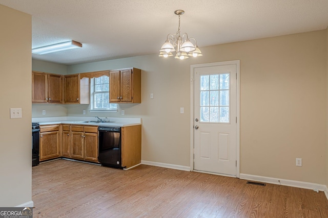 kitchen featuring decorative light fixtures, light hardwood / wood-style flooring, a textured ceiling, black dishwasher, and stove