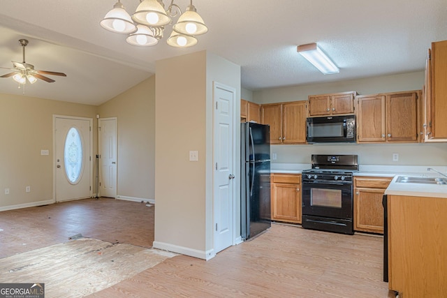 kitchen featuring lofted ceiling, sink, light hardwood / wood-style flooring, hanging light fixtures, and black appliances