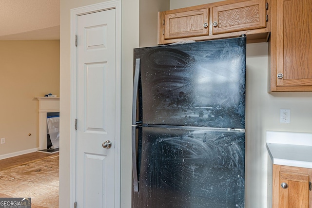 details with black refrigerator and wood-type flooring