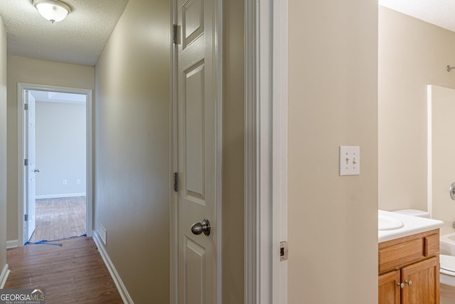 hall with dark hardwood / wood-style flooring, sink, and a textured ceiling