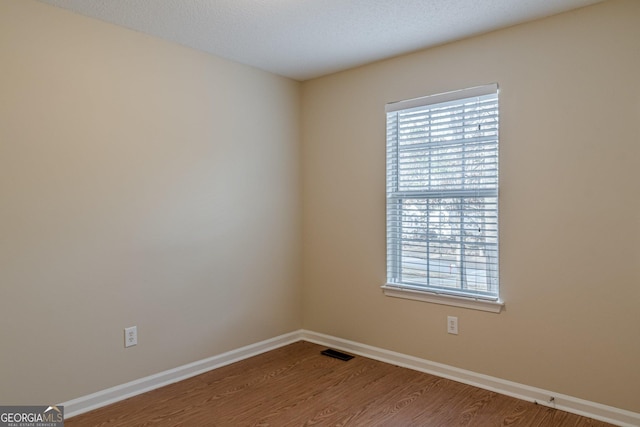 spare room featuring hardwood / wood-style floors and a healthy amount of sunlight