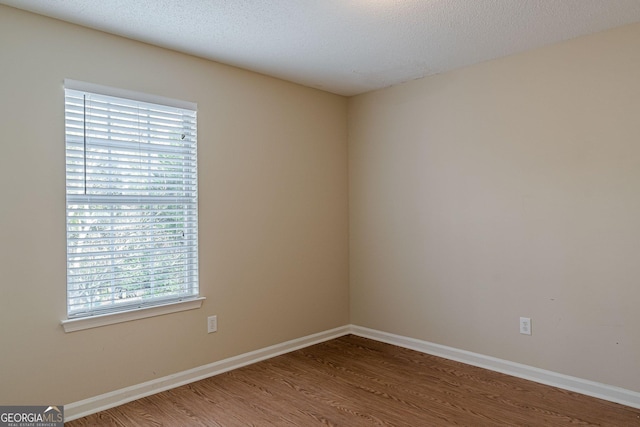 empty room with wood-type flooring and a textured ceiling