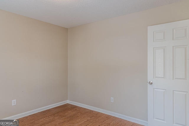 unfurnished room with light hardwood / wood-style flooring and a textured ceiling