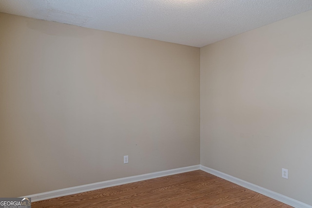 empty room featuring wood-type flooring and a textured ceiling