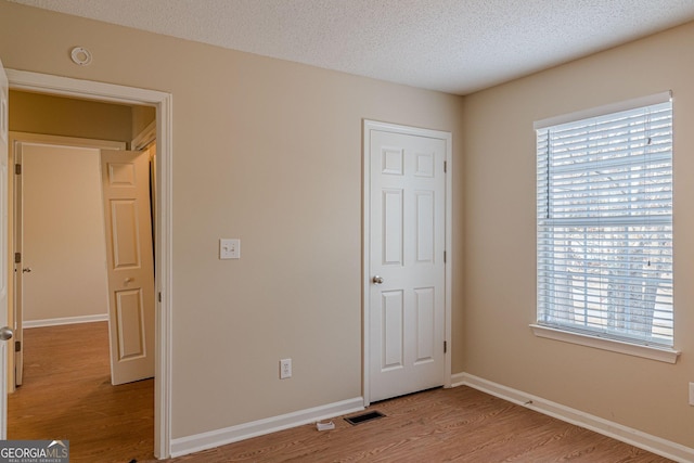 unfurnished bedroom with a textured ceiling and light hardwood / wood-style floors