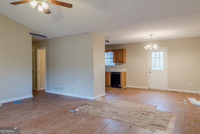 interior space with ceiling fan with notable chandelier, vaulted ceiling, light hardwood / wood-style floors, and a textured ceiling