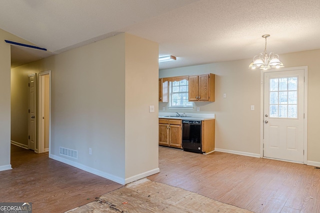 kitchen with pendant lighting, dishwasher, light wood-type flooring, a chandelier, and a textured ceiling