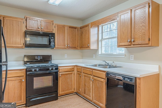 kitchen with sink, light hardwood / wood-style flooring, black appliances, and a textured ceiling