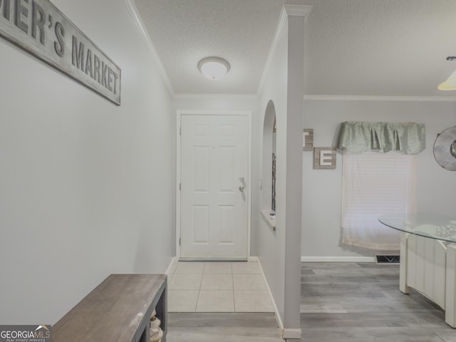 hall featuring ornamental molding, a textured ceiling, and light tile patterned floors