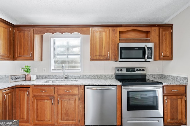 kitchen with stainless steel appliances, sink, a textured ceiling, light stone counters, and crown molding