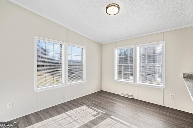 empty room featuring a textured ceiling, crown molding, and dark hardwood / wood-style floors