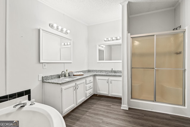 bathroom with a textured ceiling, a shower with shower door, hardwood / wood-style flooring, vanity, and crown molding