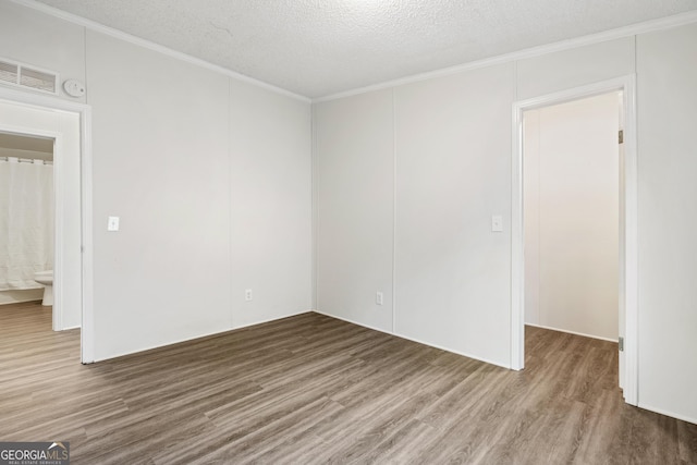 spare room featuring a textured ceiling, hardwood / wood-style floors, and crown molding