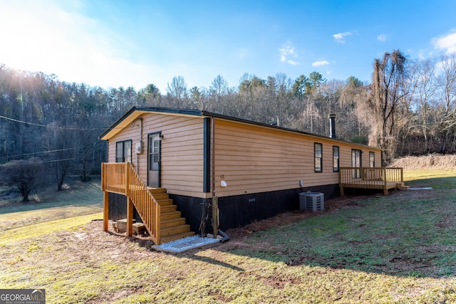 view of side of home with a deck, central air condition unit, and a lawn