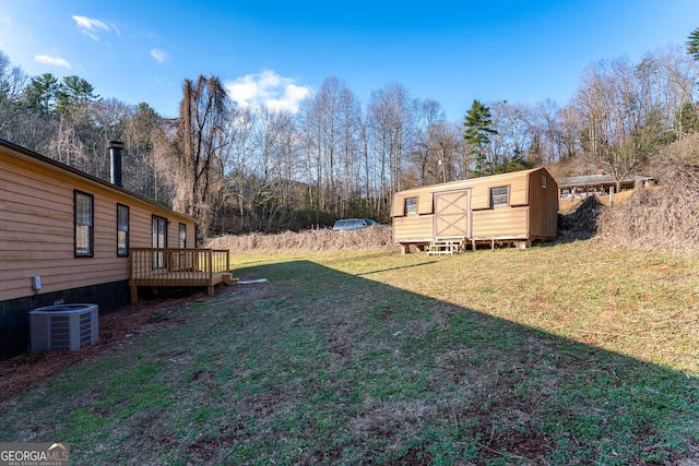 view of yard featuring cooling unit, a deck, and a storage shed