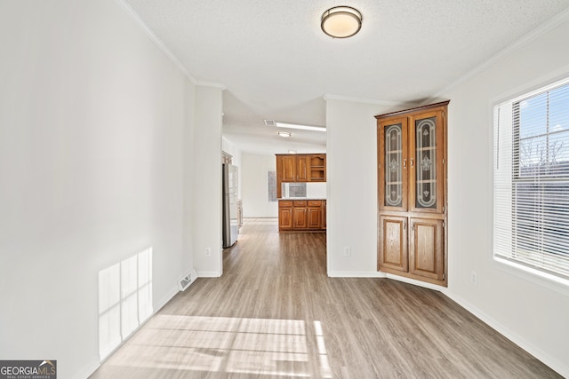 interior space featuring a textured ceiling, ornamental molding, and light hardwood / wood-style floors