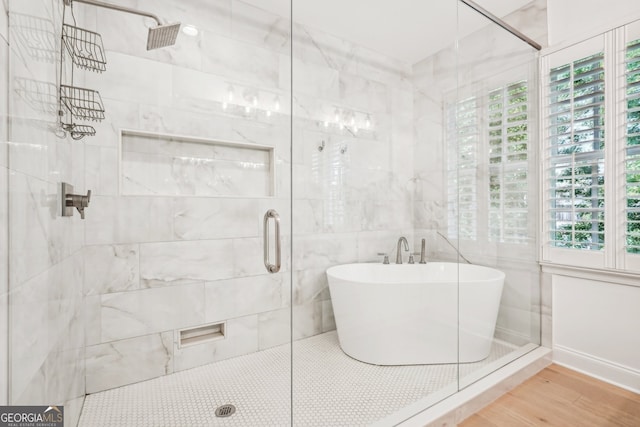 bathroom with a wealth of natural light, independent shower and bath, tile walls, and wood-type flooring