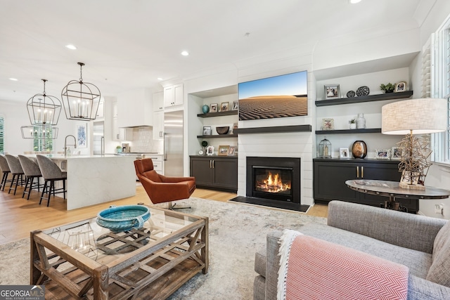 living room with sink, light wood-type flooring, and crown molding