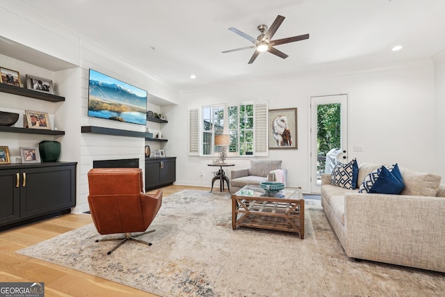 living room featuring ceiling fan, light wood-type flooring, and crown molding