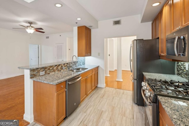 kitchen featuring sink, ceiling fan, light stone counters, kitchen peninsula, and stainless steel appliances