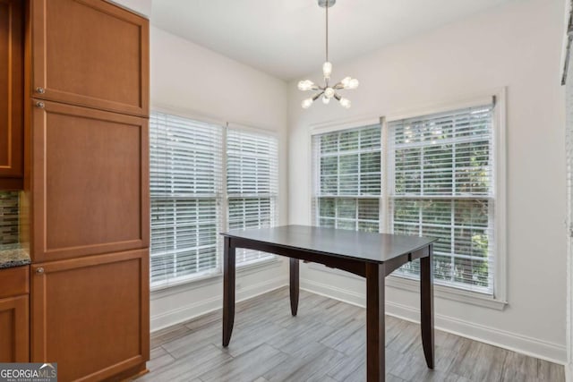 unfurnished dining area with light hardwood / wood-style floors, a wealth of natural light, and an inviting chandelier