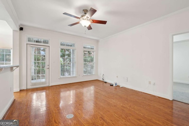 empty room with ceiling fan, wood-type flooring, and ornamental molding