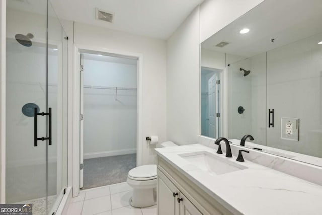 bathroom featuring tile patterned floors, a shower with door, vanity, and toilet