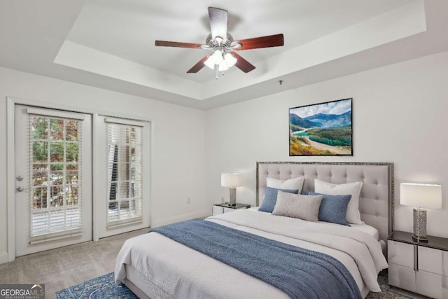 bedroom featuring a raised ceiling, access to exterior, ceiling fan, and carpet floors