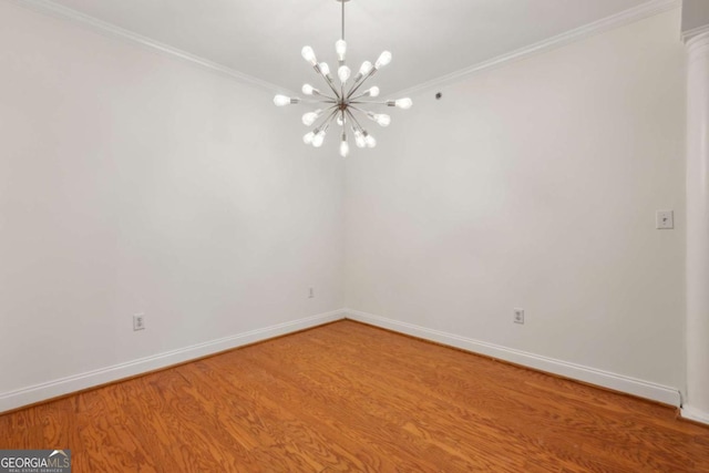 unfurnished room featuring hardwood / wood-style flooring, ornamental molding, and an inviting chandelier