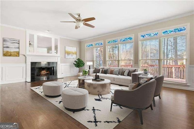 living room with a wealth of natural light, ceiling fan, dark wood-type flooring, and ornamental molding