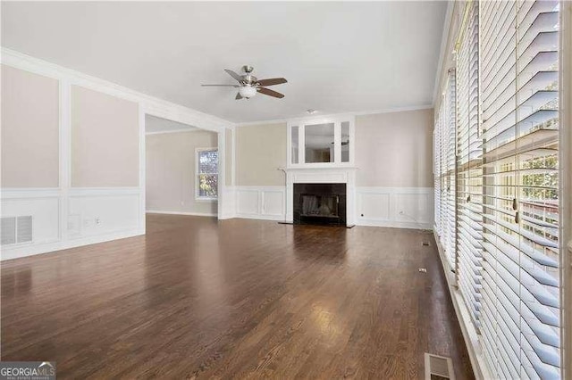 unfurnished living room with dark wood-type flooring, ceiling fan, and ornamental molding