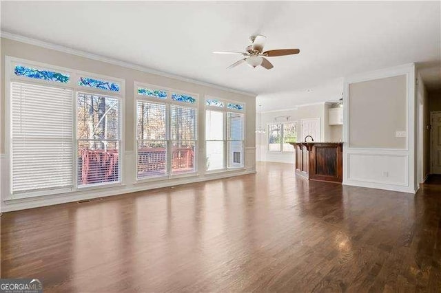 unfurnished living room with ceiling fan, plenty of natural light, and crown molding