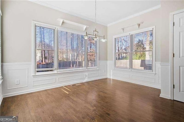 unfurnished dining area featuring dark hardwood / wood-style flooring, ornamental molding, and a notable chandelier