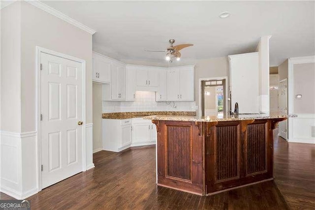 kitchen with light stone countertops, dark hardwood / wood-style floors, white cabinetry, and ceiling fan