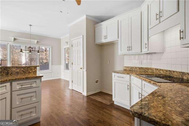 kitchen with white cabinets, black electric stovetop, ornamental molding, and dark stone counters