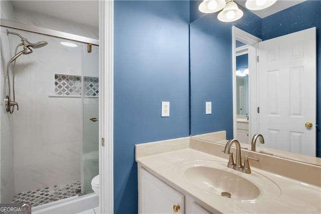 bathroom with toilet, a tile shower, and vanity