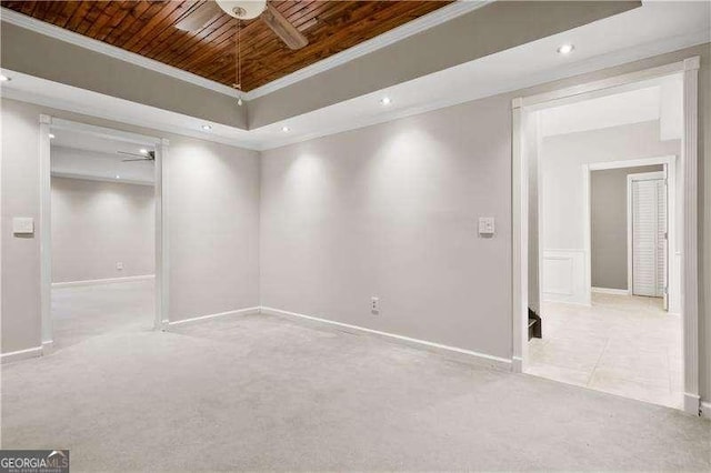 carpeted spare room with ceiling fan, wooden ceiling, crown molding, and a tray ceiling