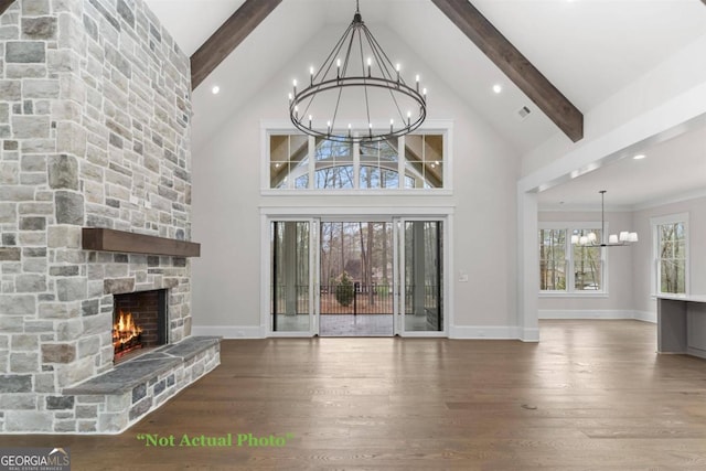 unfurnished living room featuring beam ceiling, a towering ceiling, a stone fireplace, and hardwood / wood-style floors